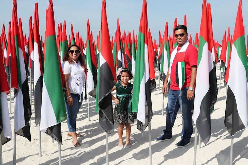 (L-R) Anju Jacob, Evelyn and Sebin Dcruz at the flag garden near Dubai's kite beach on the UAE’s 50th National Day. Pawan Singh / The National