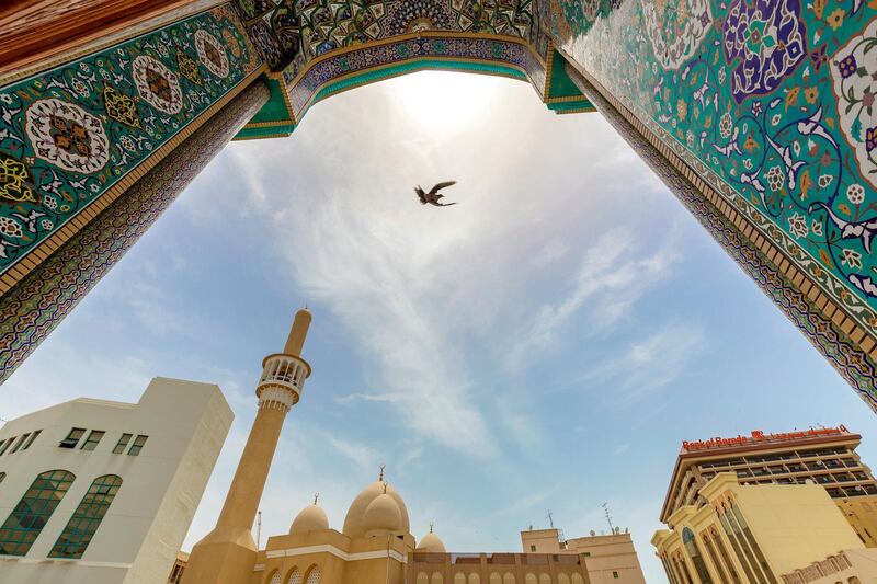 Dubai, United Arab Emirates - May 20, 2019: A bird flies in between two mosques in Bur Dubai. Monday the 20th of May 2019. Bur Dubai, Dubai. Chris Whiteoak / The National