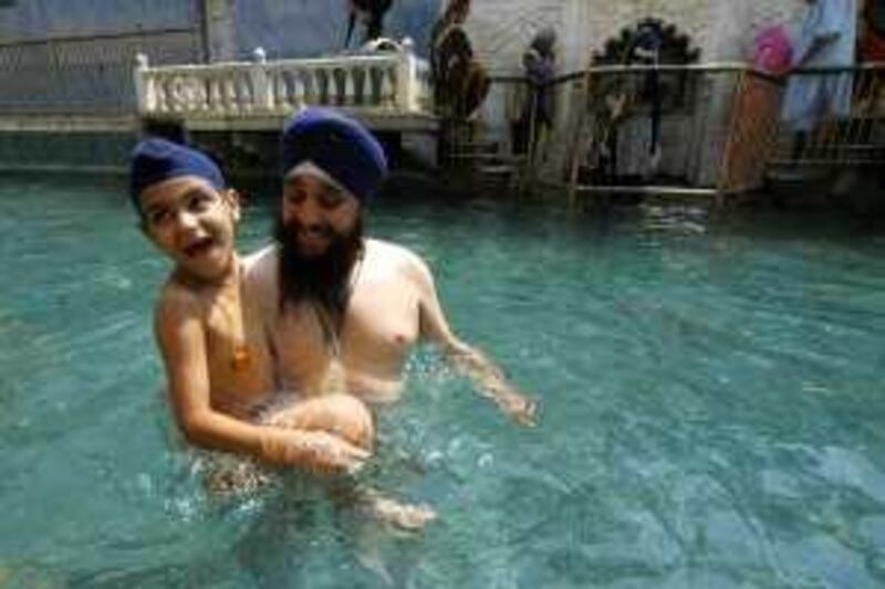 HASANABDAL: PAKISTAN: 16-July-2009.
A Pakistani Sikh and his son from Buner area of North Western Frontier province (NWFP), prepare for a dip in the holy water of Punja Sahib temple in Hasanabdal. More than 200 sikh families are taking refuge at the temple as Internally Displaced People or IDPs, following a military operation against Pakistani Taliban in Buner, Malakand, Swat and Dir areas of the NWFP. Photo by Muzammil Pasha for The National *** Local Caption ***  temple 0788.jpg