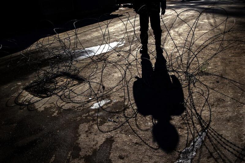 The shadow of an Indian paramilitary is seen cast over barbed wire at a checkpoint during curfew in Srinagar, Kashmir.  Dar Yasin / AP Photo