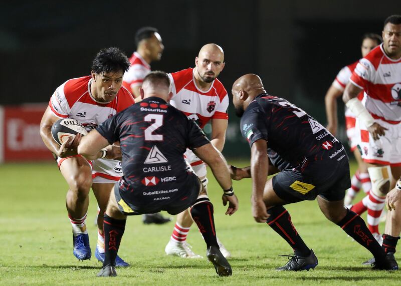 Dubai Tigers' Dueane Aholelei runs with the ball as Dubai Exiles players attempt a tackle.
