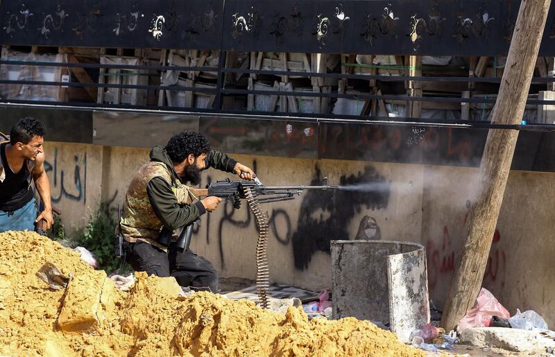 TOPSHOT - A Libyan fighter loyal to the Government of National Accord (GNA) fires a machine gun during clashes with forces loyal to strongman Khalifa Haftar south of the capital Tripoli's suburb of Ain Zara, on April 10, 2019.  / AFP / Mahmud TURKIA
