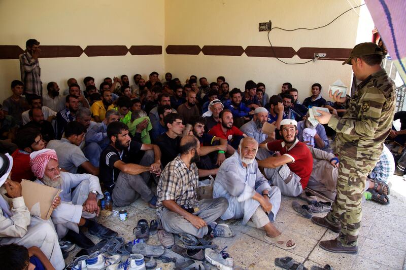 In this 12 August, 2017, photo, civilian men from the Iraqi town of Tel Afar wait to undergo security screening at a collection point for displaced people west of Mosul. Hundreds of people a day are fleeing the town and the villages around it in anticipation of a government offensive against one of the last urban centers under Islamic State group control in northern Iraq. (AP Photo/Balint Szlanko)