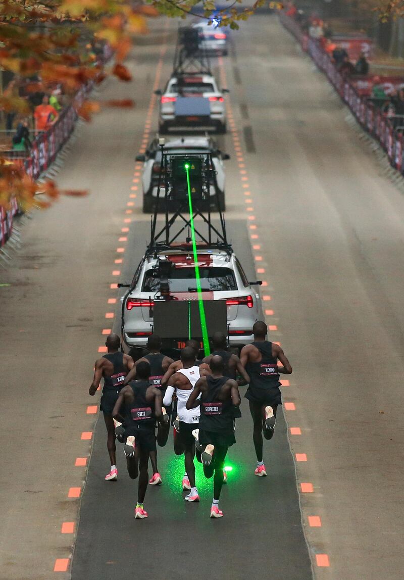 Eliud Kipchoge, white vest, runs behind his pacemaking team following the timing vehicle which is projecting a green laser to guide them during the Kenyan's successful attempt to run a sub two-hour marathon  in the Ineos 1:59 Challenge on Sunday, October 12. AP