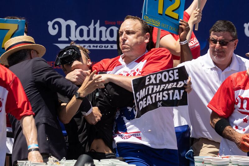 Joey Chestnut tackles a protester who interrupted the competition during the 2022 Nathan's Famous Fourth of July hot dog eating contest on Coney Island on July 4, 2022 in New York.  - Joey Chestnut won by eating 63 hot dogs and buns.  (Photo by Yuki IWAMURA  /  AFP)