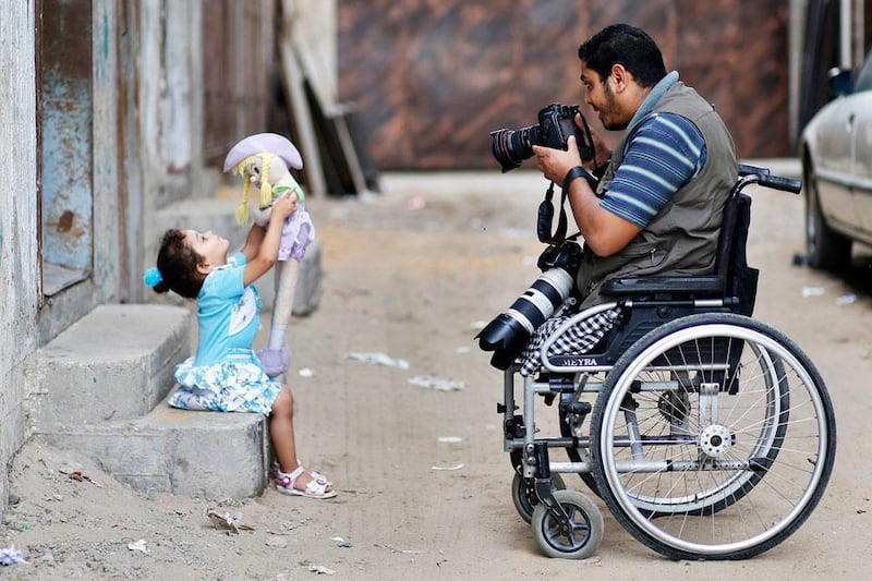 Moamen Qreiqea takes pictures of his daughter outside his home in Gaza City.