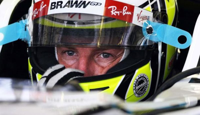 Above, the F1 world champion Jenson Button in the cockpit of his Brawn GP car as he prepares for his first practice round yesterday.
