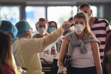 A health worker checks the body temperature of passengers bound for Frankfurt at Dubai International Airport. AFP