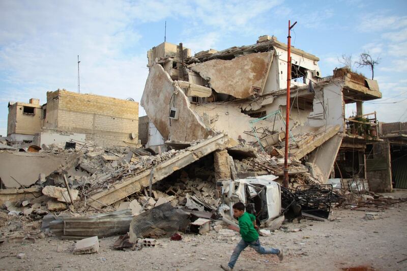 A Syrian boy runs past a destroyed building during air strikes by regime forces in the rebel-held town of Douma, in the besieged Eastern Ghouta region. Hamza Al-Ajweh / AFP