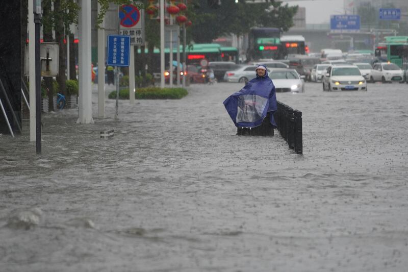 A Zhengzhou resident, prepared for the worst with a rain cape, on a flooded road.