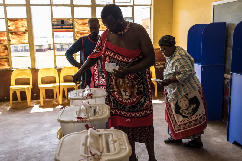 A voter in traditional attire casts his ballot next to a woman wearing traditional lihiya during Eswatini's parliamentary elections. AFP
