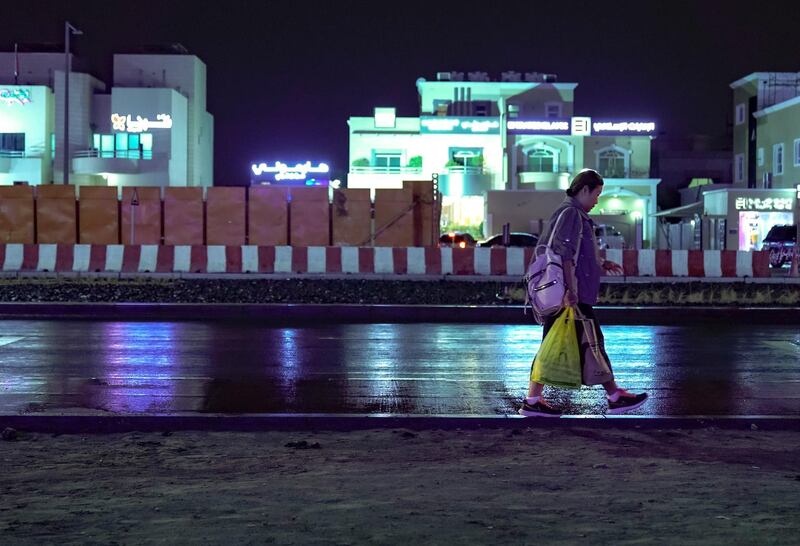 Abu Dhabi, United Arab Emirates, January 9, 2020.  A lady does a balancing act on the sidewalk with her groceries as it pours at Khalifa City.    
Victor Besa / The National