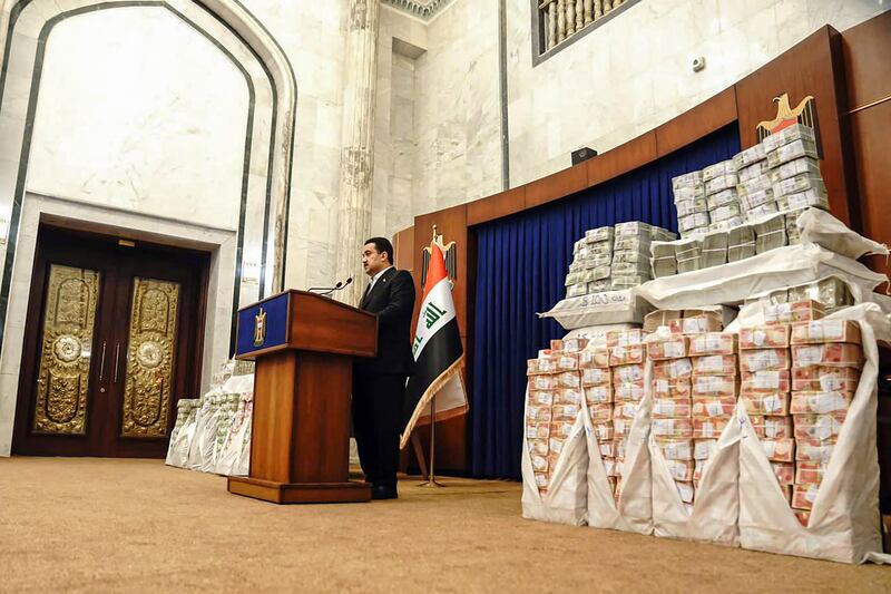 Iraq's Prime Minister Mohammed Shia Al Sudani displays piles of cash that were recovered from $2. 5 billion of snatched government funds last year. AFP