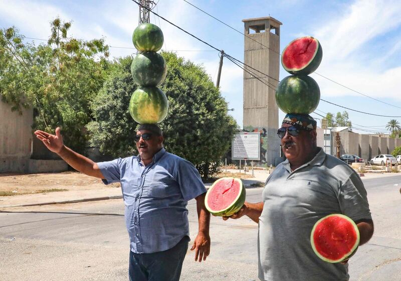 Palestinian watermelon vendors put on a show to attract customers, in a street at the entrance of the West Bank town of Jericho. AFP