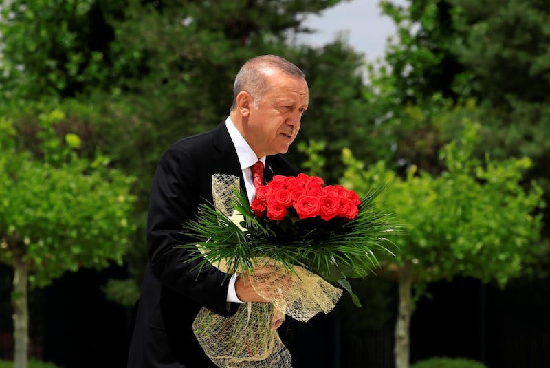Turkish President Tayyip Erdogan carries flowers to a monument during a ceremony marking the third anniversary of the attempted coup, at the Presidential Palace in Ankara, Turkey.  REUTERS