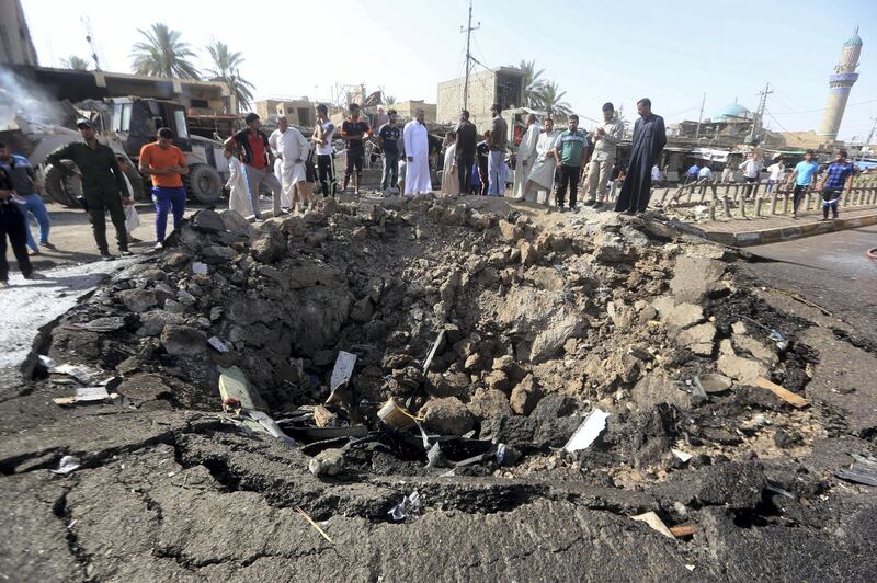 Iraqi men look at a crater left by a massive suicide car bomb attack carried out the previous day by the Islamic State group in the predominantly Shiite town of Khan Bani Saad, 20 km north of Baghdad, on July 18, 2015. The suicide attack by the IS group was one of the deadliest since it took over swathes of Iraq last year and came as the country marked Eid al-Fitr, the Muslim feast that ends the fasting month of Ramadan. AFP PHOTO / AHMAD AL-RUBAYE (Photo by AHMAD AL-RUBAYE / AFP)
