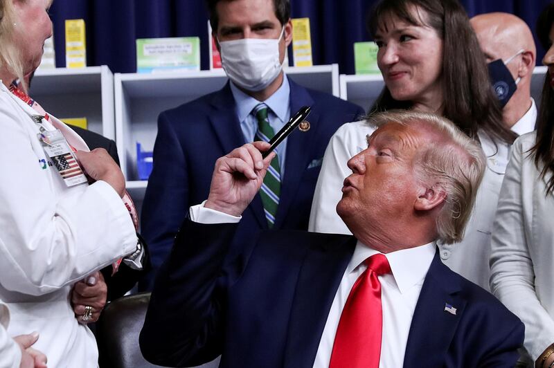 US President Donald Trump presents a gift pen he used to sign executive orders on lowering drug prices during a signing ceremony in the Eisenhower Executive Office Building at the White House in Washington, US.  Reuters