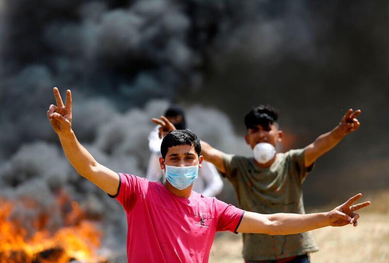 Palestinian demonstrators cover their faces as they burn tyres during a protest. Mohammed Abed / AFP