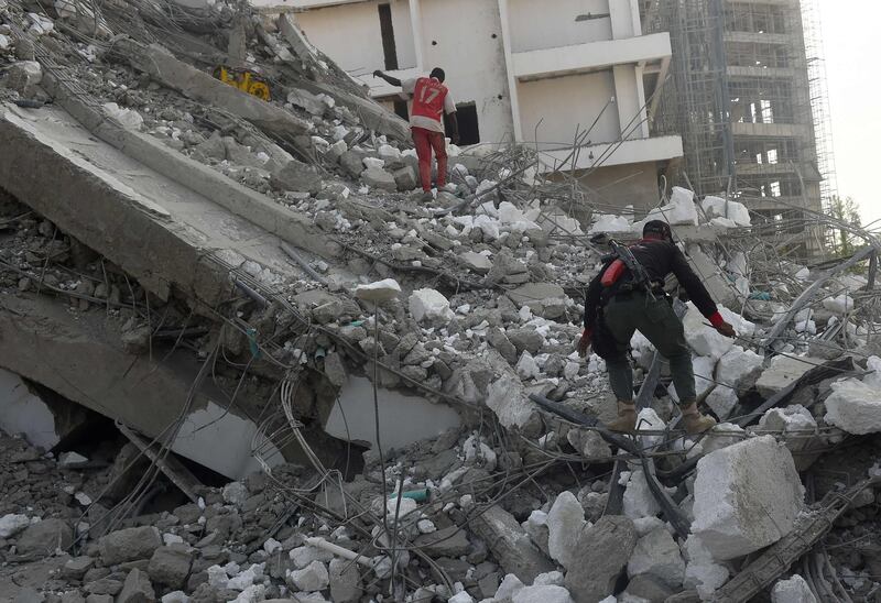 A police orderly climbs to search for his boss in the rubble.  AFP