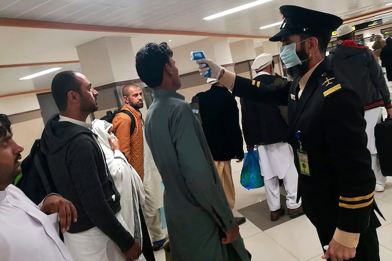 An airport official checks the temperature of a passenger upon his arrival at the Bacha Khan International Airport in Peshawar.  AFP
