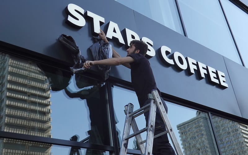 A worker unveils the name of the Stars Coffee chain, which is opening in former Starbucks coffee shops in Russia, at a store on Novy Arbat street, in Moscow, Russia.   EPA