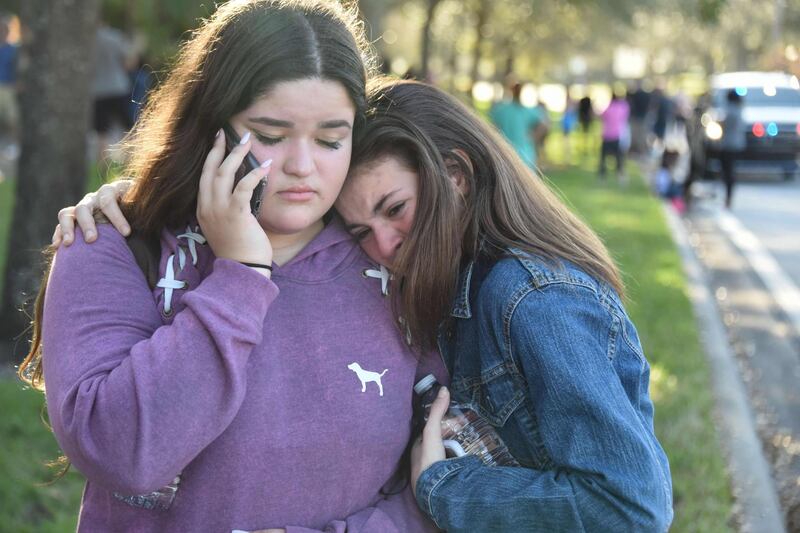 Students react following a shooting at Marjory Stoneman Douglas High School in Parkland, Florida, a city about 50 miles (80 kilometers) north of Miami on February 14, 2018.
A gunman opened fire at the Florida high school, an incident that officials said caused "numerous fatalities" and left terrified students huddled in their classrooms, texting friends and family for help.
The Broward County Sheriff's Office said a suspect was in custody. / AFP PHOTO / Michele Eve Sandberg