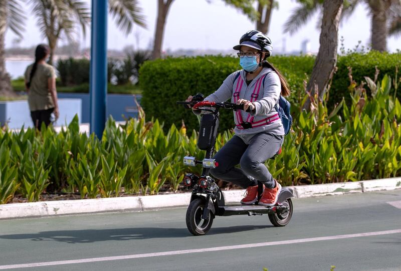 A lady rides her e-scooter to work in the morning along the Corniche, Abu Dhabi on May 5th, 2021. Victor Besa / The National.