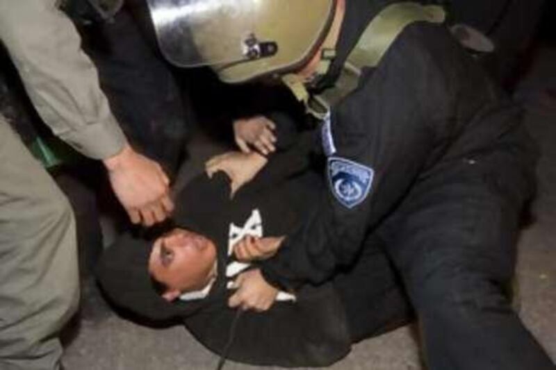 Israeli border policemen detain a settler during clashes outside a disputed house in the flashpoint West Bank city of Hebron on December 3, 2008. Israeli settlers and supporters prepared to battle a forceful eviction today after Israel declared a closed military area around the house, occupied in defiance of a court order. The settlers insist they have not only a God-given right to all of the biblical land of Israel, but that they are also legally in the house that a Jewish-American businessman claims he bought so more Jews can live in Hebron. The original Palestinian owner denies selling it, and the High Court has ordered the settlers out until ownership can be determined. AFP PHOTO/MENAHEM KAHANA *** Local Caption ***  835080-01-08.jpg