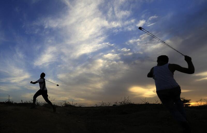 Palestinian protesters use slingshots to throw stones towards Israeli soldiers during clashes in Gaza. (Mohammed Abed / AFP)