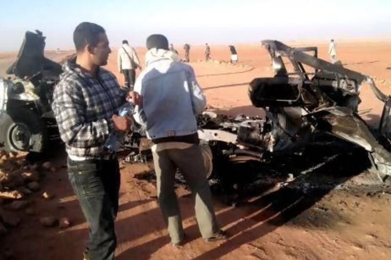 Men inspect the wreckage of a vehicle near the In Amenas gas plant. Algerian bomb squads scoured the plant where Islamist militants took dozens of foreign workers hostage searching for explosive traps.