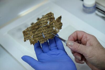 A worker of the Israeli Antiquity Authority sews fragments of the Dead Sea scrolls which includes biblical verses in a preservation laboratory of the Israel Museum in Jerusalem. Getty Images
