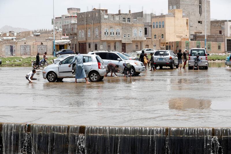 Yemenis wash vehicles with rainwater at a flooded stream of rainwater in Sanaa, Yemen.  EPA