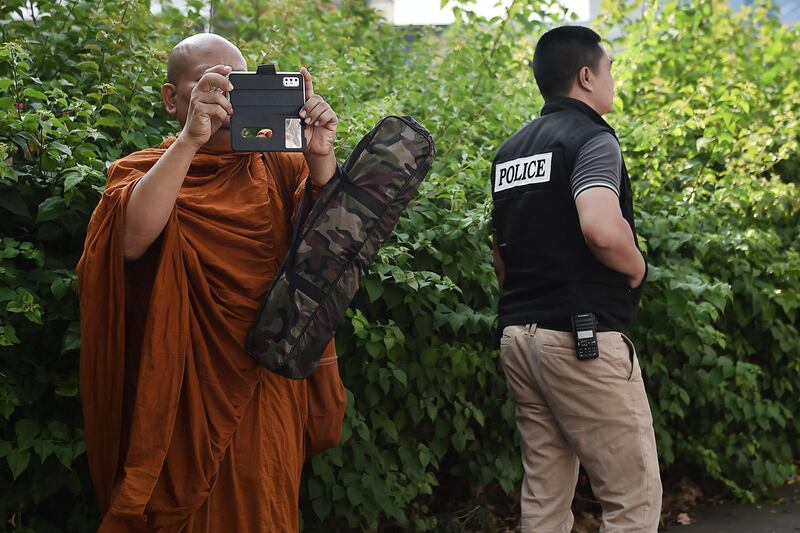 A monk uses hi mobile phone to observe the situation outside the Terminal 21 mall, where a mass shooting took place, in the Thai northeastern city of Nakhon Ratchasima.   AFP