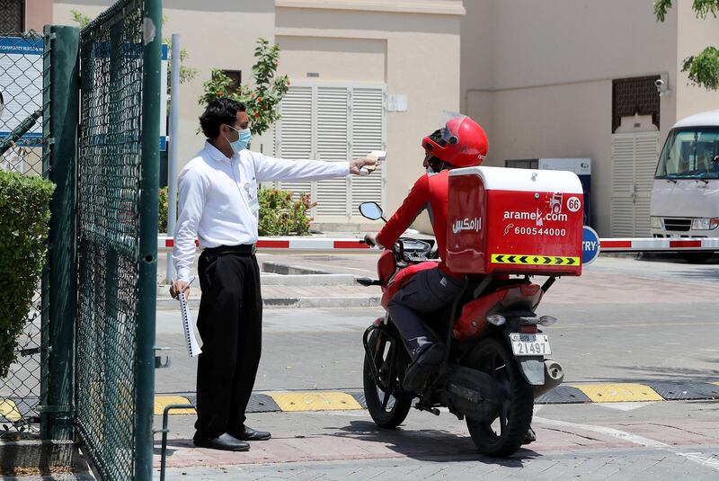DUBAI, UNITED ARAB EMIRATES , April 17– 2020 :- One of the security guard taking  body temperature of the delivery driver in Al Furjan area in Dubai. Dubai is conducting 24 hours sterilisation programme across all areas and communities in the Emirate and told residents to stay at home. UAE government told residents to wear face mask and gloves all the times outside the home whether they are showing symptoms of Covid-19 or not.  (Pawan Singh / The National) For News/Online/Instagram
