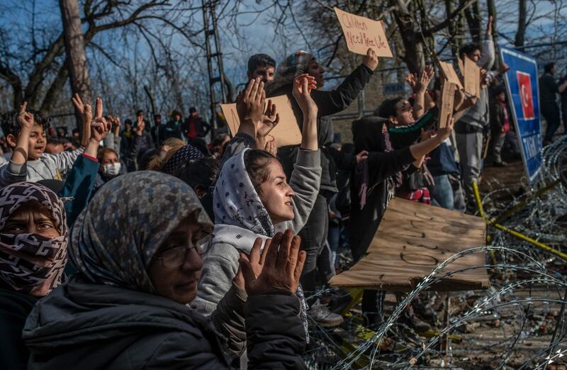 Migrants hold placards as they demonstrate, waiting at the buffer zone in front of the Pazarkule border crossing to Greece, in Edirne.  AFP