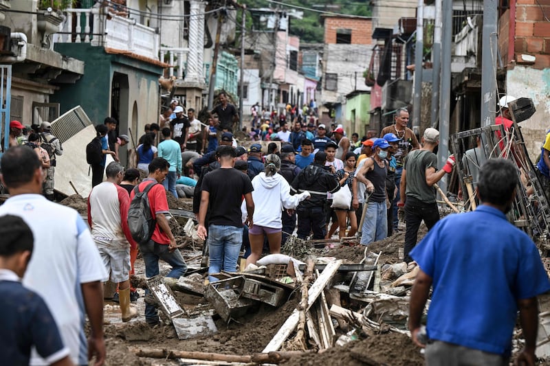Residents walk among the rubble of destroyed houses washed away by the landslide in Tejerias. AFP