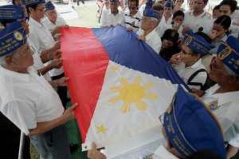 Filipino WWII veterans prepare to fold the Philippine flag which was draped on the coffin of fellow WWII veteran Andres Cruz,88, at his funeral Tuesday Feb. 17, 2009 at Malolos town, 40 kilometers north of Manila, Philippines. US President Barack Obama is to sign Tuesday in Washington a US $198-million compensation package for Filipino WWII veterans included in the US stimulus package approved by US Congress Friday. It is not clear however if Cruz will be entitled to such benefits.  (AP Photo/Bullit Marquez) *** Local Caption ***  XBM106_Philippines_US_WWII_Veterans.jpg
