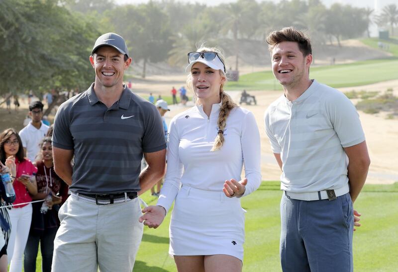 Niall Horan, right, with Rory McIlroy, left, and Paige Spiranac on the eighth tee during the pro-am at Emirates Golf Club. David Cannon / Getty Images