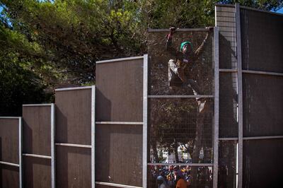 A migrant climbs a fence to exit an immigration centre on the Italian island of Lampedusa. AFP