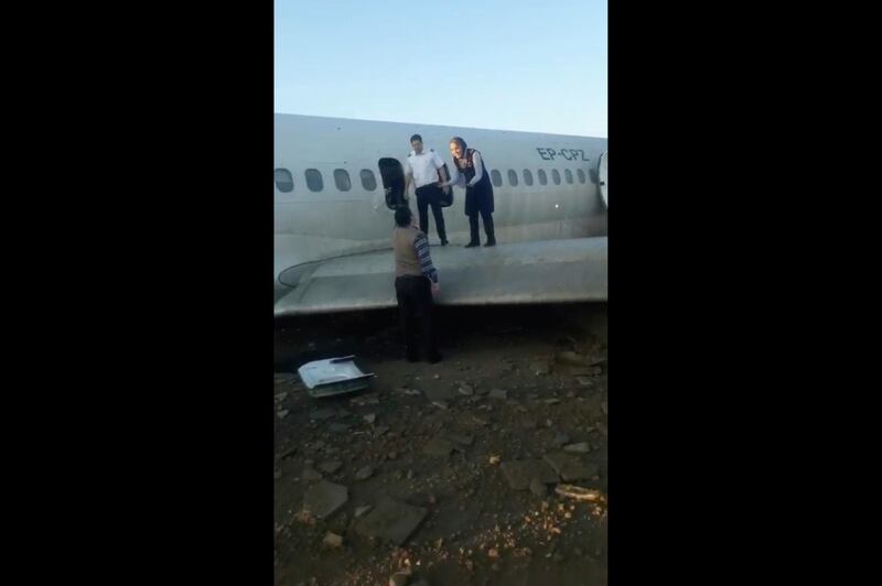 A flight attendant speaks to an onlooker as passengers use a wing of the crashed plane to reach safety. AP