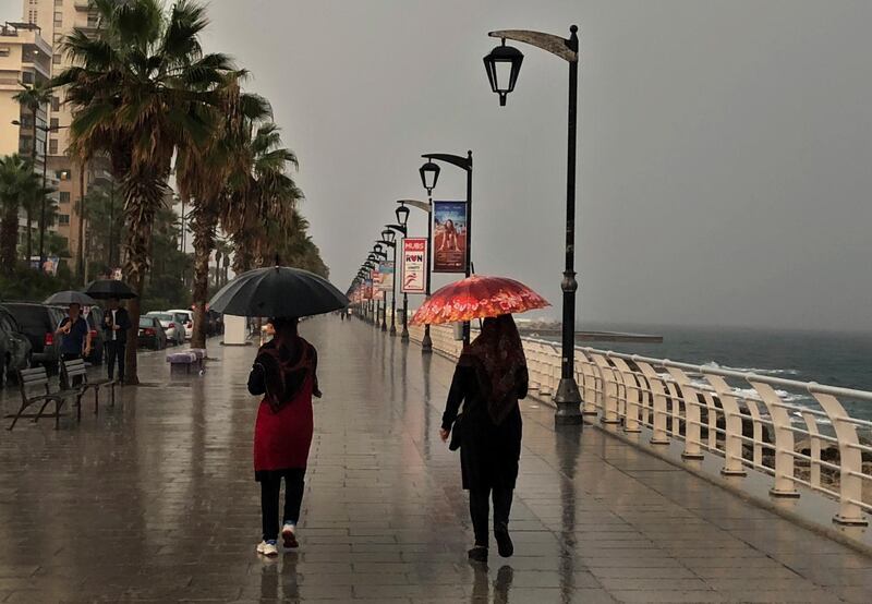 Lebanese women take shelter under their umbrellas on the Corniche along the Beirut coastline, or waterfront promenade, in Beirut, Lebanon, Sunday, Oct. 21, 2018. (AP Photo/Hussein Malla)