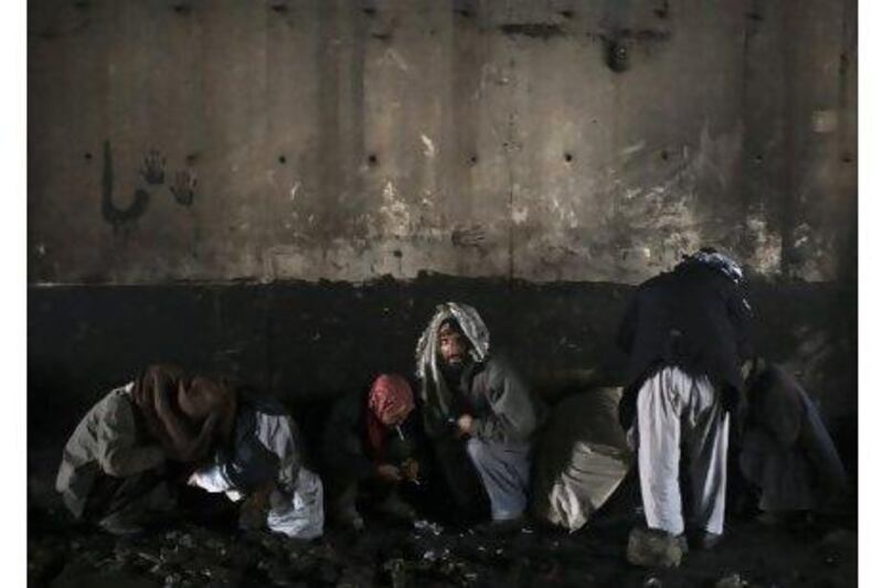 Afghan drug addicts cover their heads with scarves as they use drugs under a bridge inhabited by drug addicts in Kabul. Ahmad Masood / Reuters