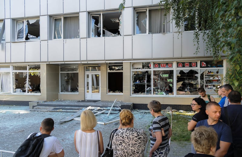 Locals inspect the damage to a building near the impact area of a rocket strike in Lviv. EPA