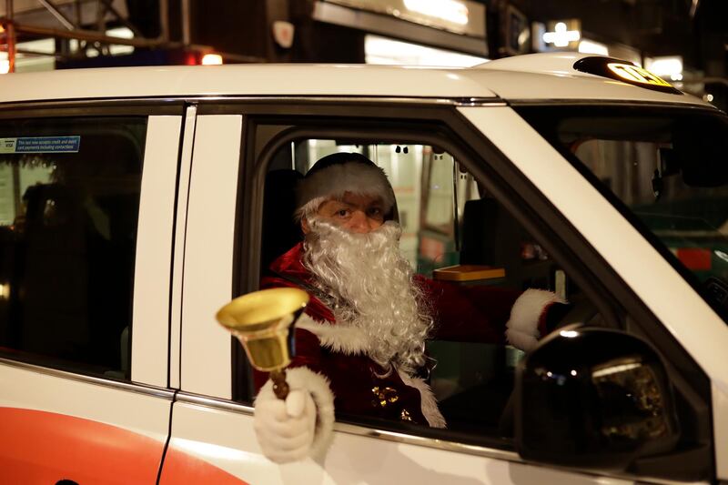 London taxi driver Michael Harris, dressed as Santa Claus, who said he was in hospital with coronavirus for three weeks earlier in the year, poses for photographs in his cab parked outside Burlington Arcade in London. AP Photo