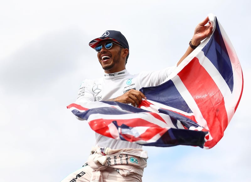 NORTHAMPTON, ENGLAND - JULY 10:  Lewis Hamilton of Great Britain and Mercedes GP stands on top of a fence with a Great Britain flag to celebrate his win with the British fans during the Formula One Grand Prix of Great Britain at Silverstone on July 10, 2016 in Northampton, England.  (Photo by Clive Mason/Getty Images)