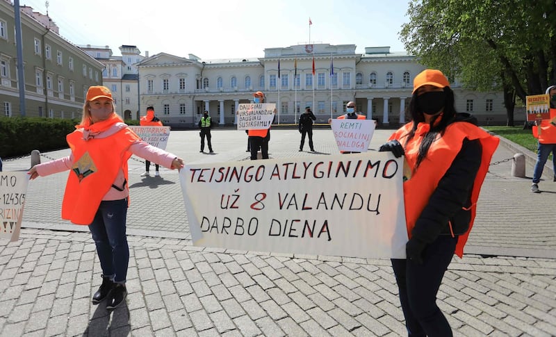 Members of the Lithuanian Trade Union "Solidarity", wearing protective masks and respecting the social distancing rules against the spread of the novel coronavirus, COVID-19, protest in front of the Lithuanian Presidential Palace during the Labour Day demonstration in Vilnius the poster reads "Equitable remuneration for the 8-hour day".  AFP