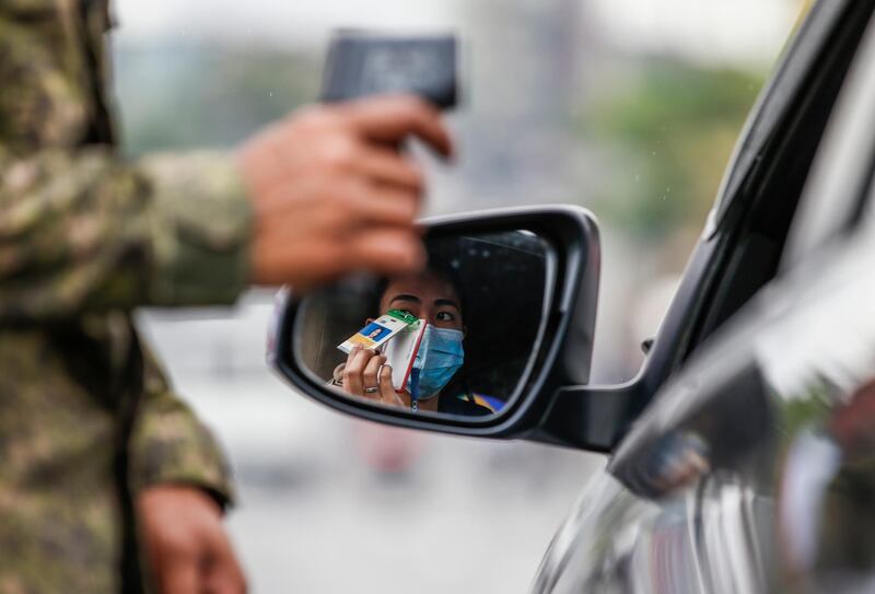 A woman in a car shows a company identification card for verification by a Philippine Army soldier to enter a quarantine border of Quezon City, Metro Manila. EPA