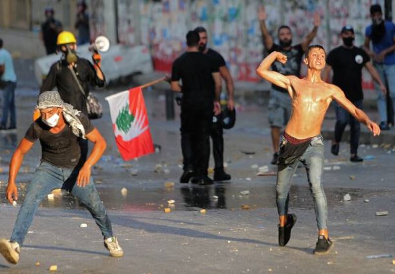 Lebanese protesters throw stones during clashes with the army and security forces in Downtown Beirut on the anniversary of the port blast that devastated the city last year. Hundreds of Lebanese marched today to mark the cataclysmic explosion, protesting against impunity over the country's worst peacetime disaster at a time when its economy was already in tatters.