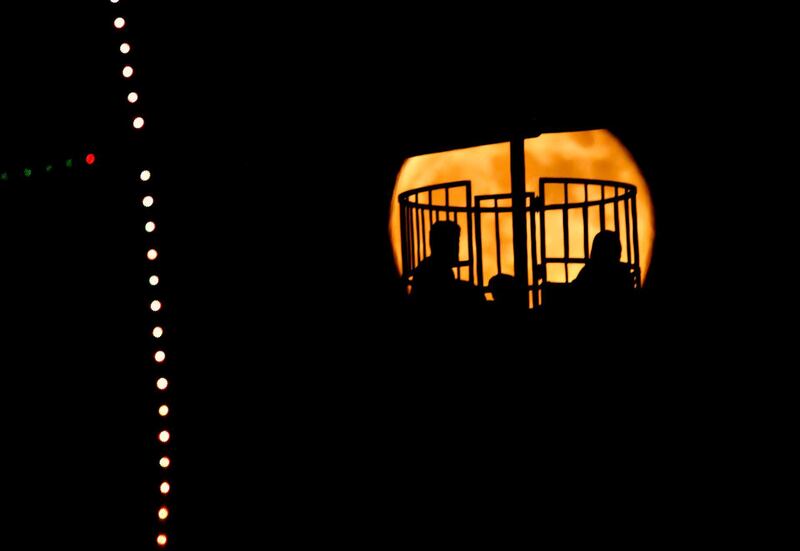 The moon rises behind people on a ride at an amusement park in Baghdad, Iraq. AP Photo