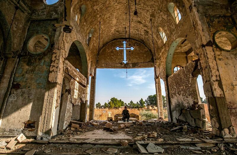 A member of the Khabour Guards (MNK) Assyrian Syrian militia, affiliated with the Syrian Democratic Forces (SDF), sits in the ruins of the Assyrian Church of the Virgin Mary, which was previously destroyed by ISIS fighters, in the village of Tal Nasri south of the town of Tal Tamr in Syria's northeastern Hasakah province. AFP